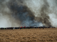 Protesters are walking past a wildfire started by a launched tear gas canister during a march as part of a rally against the construction of...