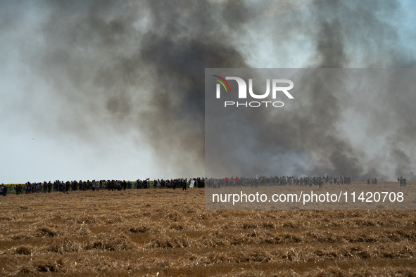 Protesters are walking past a wildfire started by a launched tear gas canister during a march as part of a rally against the construction of...