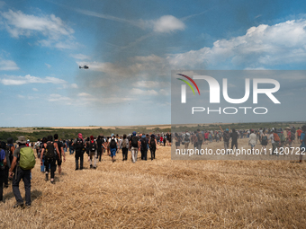 Protesters are walking past a wildfire started by a launched tear gas canister during a march as part of a rally against the construction of...