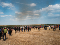 Protesters are walking past a wildfire started by a launched tear gas canister during a march as part of a rally against the construction of...