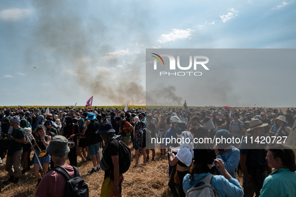 Protesters are walking past a wildfire started by a launched tear gas canister during a march as part of a rally against the construction of...