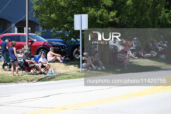 Bystanders are gathering to watch the funeral procession. Bystanders are gathering for the funeral procession of Corey Comperatore in Sarver...