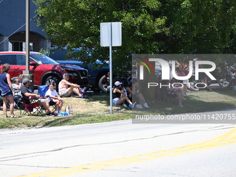 Bystanders are gathering to watch the funeral procession. Bystanders are gathering for the funeral procession of Corey Comperatore in Sarver...