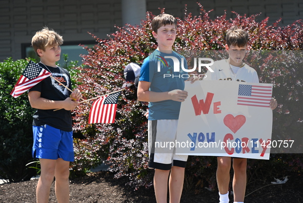 Children are holding up a sign that reads ''We Love You Corey'' at the funeral procession. Bystanders are gathering for the funeral processi...