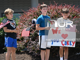 Children are holding up a sign that reads ''We Love You Corey'' at the funeral procession. Bystanders are gathering for the funeral processi...