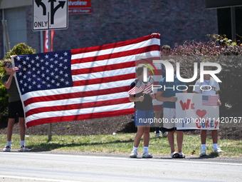 Bystanders are gathering and holding up signs and American flags for the funeral procession of Corey Comperatore in Sarver, Pennsylvania, Un...