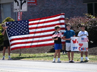 Bystanders are gathering and holding up signs and American flags for the funeral procession of Corey Comperatore in Sarver, Pennsylvania, Un...