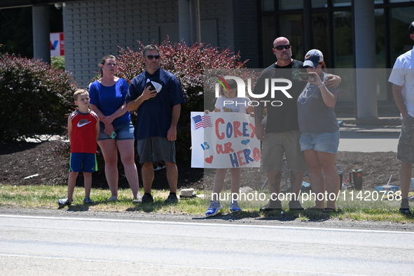 Bystanders are gathering and holding up signs and American flags for the funeral procession of Corey Comperatore in Sarver, Pennsylvania, Un...