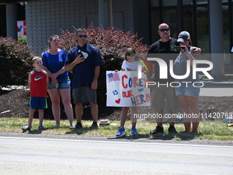 Bystanders are gathering and holding up signs and American flags for the funeral procession of Corey Comperatore in Sarver, Pennsylvania, Un...