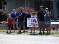 Bystanders are gathering and holding up signs and American flags for the funeral procession of Corey Comperatore in Sarver, Pennsylvania, Un...