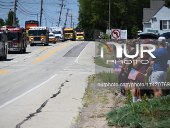 Bystanders are gathering and holding up signs and American flags for the funeral procession of Corey Comperatore in Sarver, Pennsylvania, Un...