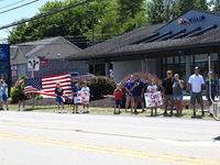 Bystanders are gathering and holding up signs and American flags for the funeral procession of Corey Comperatore in Sarver, Pennsylvania, Un...