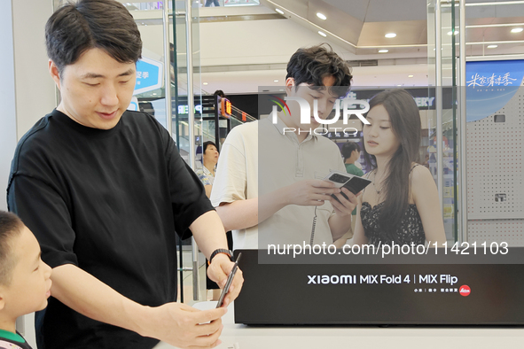 Customers are experiencing the Mi MIX Flip and MIX Fold 4 foldable phones at a Xiaomi store in Tongling, Anhui province, China, on July 19,...