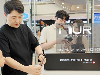 Customers are experiencing the Mi MIX Flip and MIX Fold 4 foldable phones at a Xiaomi store in Tongling, Anhui province, China, on July 19,...