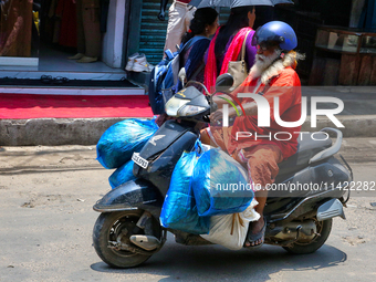 A man is carrying several bags on his scooter in the East Fort area in Thiruvananthapuram (Trivandrum), Kerala, India, on April 13, 2024. (