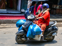 A man is carrying several bags on his scooter in the East Fort area in Thiruvananthapuram (Trivandrum), Kerala, India, on April 13, 2024. (