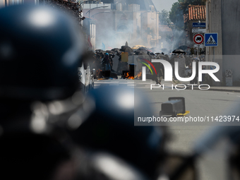 Protesters are protecting themselves behind a barricade created using rubbish cans and makeshift shields during a rally against the construc...