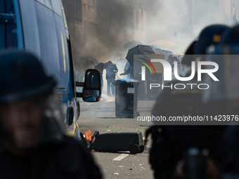 Protesters are protecting themselves behind a barricade created using rubbish cans and makeshift shields during a rally against the construc...