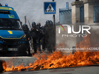 French Gendarmes are standing behind a burning rubbish barricade during a rally against the construction of a giant water reservoir (mega-ba...