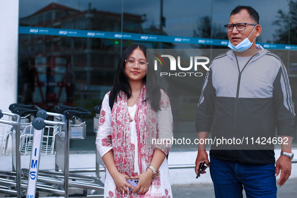 Krishpa Rai (L), a Nepali student who is arriving back from violence-hit Bangladesh, is standing alongside her father after arriving at Trib...