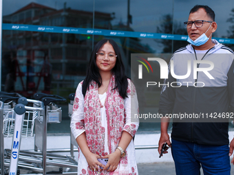 Krishpa Rai (L), a Nepali student who is arriving back from violence-hit Bangladesh, is standing alongside her father after arriving at Trib...