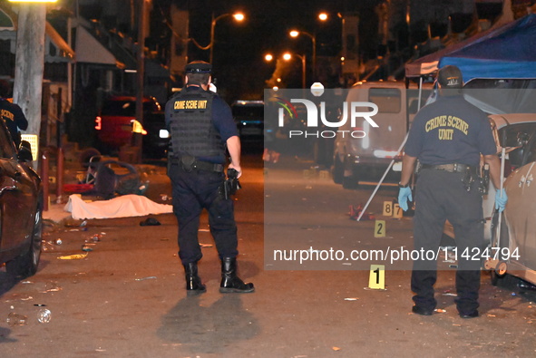 The crime scene unit is at the scene of a mass shooting with evidence markers placed on the ground, in Philadelphia, Pennsylvania, on July 2...