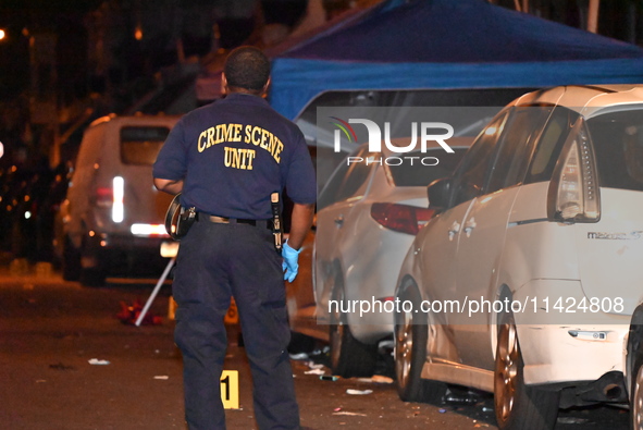 The crime scene unit is at the scene of a mass shooting with evidence markers placed on the ground, in Philadelphia, Pennsylvania, on July 2...