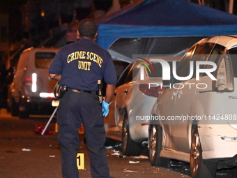 The crime scene unit is at the scene of a mass shooting with evidence markers placed on the ground, in Philadelphia, Pennsylvania, on July 2...