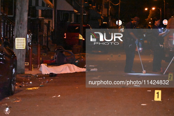 The crime scene unit is at the scene of a mass shooting with evidence markers placed on the ground, in Philadelphia, Pennsylvania, on July 2...