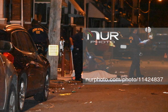 The crime scene unit is at the scene of a mass shooting with evidence markers placed on the ground, in Philadelphia, Pennsylvania, on July 2...