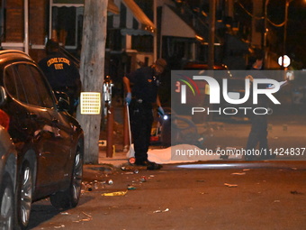 The crime scene unit is at the scene of a mass shooting with evidence markers placed on the ground, in Philadelphia, Pennsylvania, on July 2...