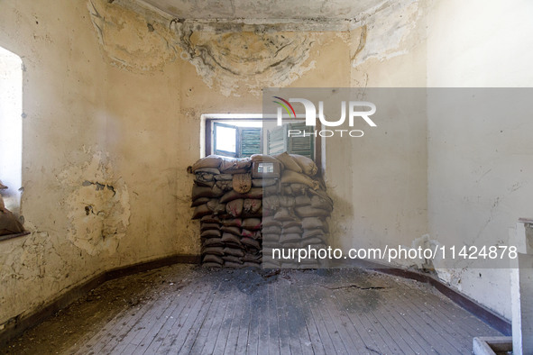 Sandbags behind a window are being seen inside an abandoned house next to the buffer zone, which is being used as a defensive point during t...