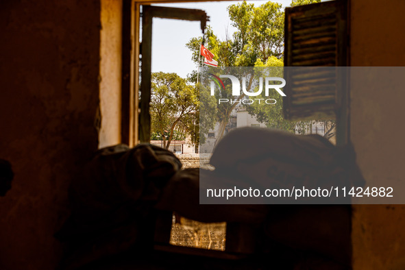 The flags of Turkey and the self-declared ''Turkish Republic of Northern Cyprus'' are being seen through a window of an abandoned house, whi...