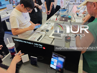 Customers are experiencing two fold-screen phones newly released by Xiaomi at a Xiaomi Home in Shanghai, China, on July 21, 2024. (