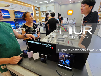 Customers are experiencing two fold-screen phones newly released by Xiaomi at a Xiaomi Home in Shanghai, China, on July 21, 2024. (