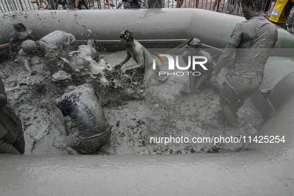 Visitors are playing in a mud pool at Mud Festival Park in Boryeong, South Korea. The Boryeong Mud Festival is an annual festival that takes...