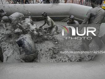 Visitors are playing in a mud pool at Mud Festival Park in Boryeong, South Korea. The Boryeong Mud Festival is an annual festival that takes...