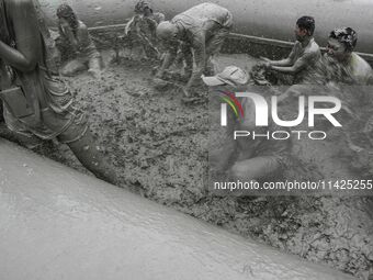 Visitors are playing in a mud pool at Mud Festival Park in Boryeong, South Korea. The Boryeong Mud Festival is an annual festival that takes...