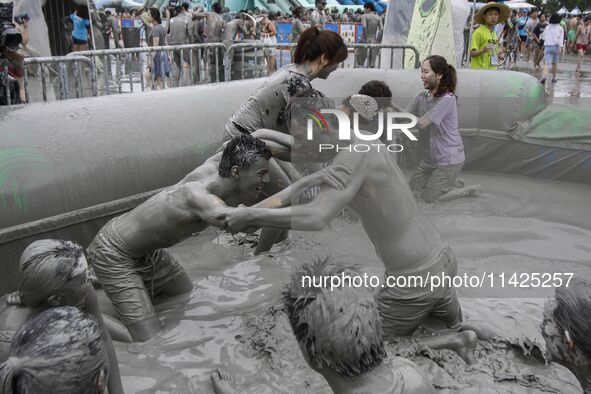 Visitors are playing in a mud pool at Mud Festival Park in Boryeong, South Korea. The Boryeong Mud Festival is an annual festival that takes...