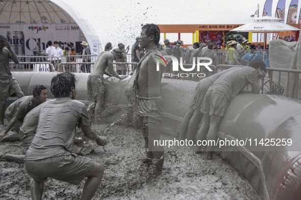 Visitors are playing in a mud pool at Mud Festival Park in Boryeong, South Korea. The Boryeong Mud Festival is an annual festival that takes...