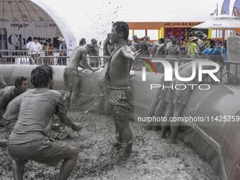 Visitors are playing in a mud pool at Mud Festival Park in Boryeong, South Korea. The Boryeong Mud Festival is an annual festival that takes...