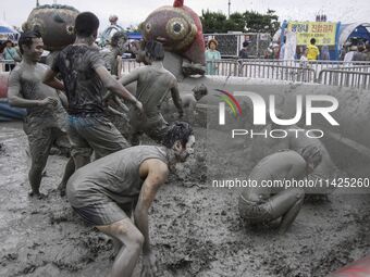 Visitors are playing in a mud pool at Mud Festival Park in Boryeong, South Korea. The Boryeong Mud Festival is an annual festival that takes...