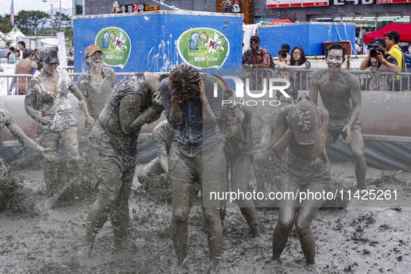 Visitors are playing in a mud pool at Mud Festival Park in Boryeong, South Korea. The Boryeong Mud Festival is an annual festival that takes...