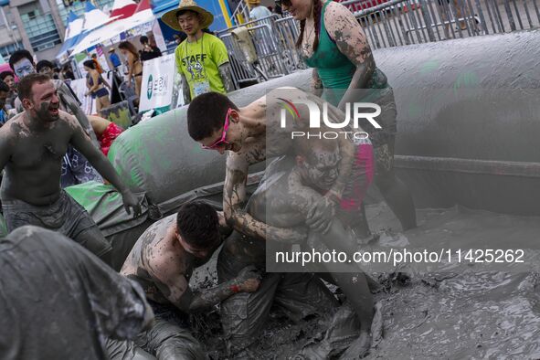 Visitors are playing in a mud pool at Mud Festival Park in Boryeong, South Korea. The Boryeong Mud Festival is an annual festival that takes...