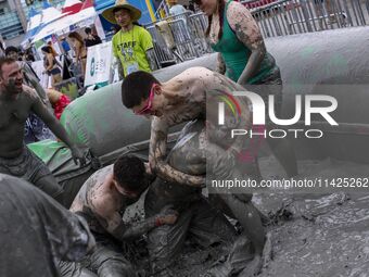 Visitors are playing in a mud pool at Mud Festival Park in Boryeong, South Korea. The Boryeong Mud Festival is an annual festival that takes...