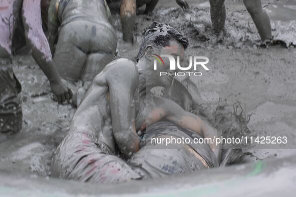 Visitors are playing in a mud pool at Mud Festival Park in Boryeong, South Korea. The Boryeong Mud Festival is an annual festival that takes...