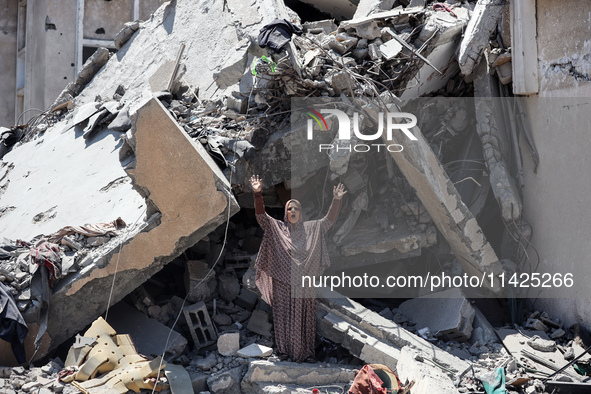 A Palestinian woman is gesturing near debris and destroyed vehicles in Nuseirat in the central Gaza Strip, on July 21, 2024, following an Is...