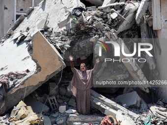 A Palestinian woman is gesturing near debris and destroyed vehicles in Nuseirat in the central Gaza Strip, on July 21, 2024, following an Is...