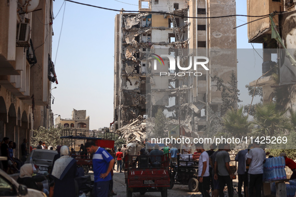 Palestinians are checking the rubble of buildings that were destroyed following an Israeli air strike on a residential building, amid the Is...