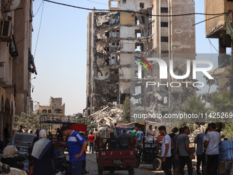 Palestinians are checking the rubble of buildings that were destroyed following an Israeli air strike on a residential building, amid the Is...